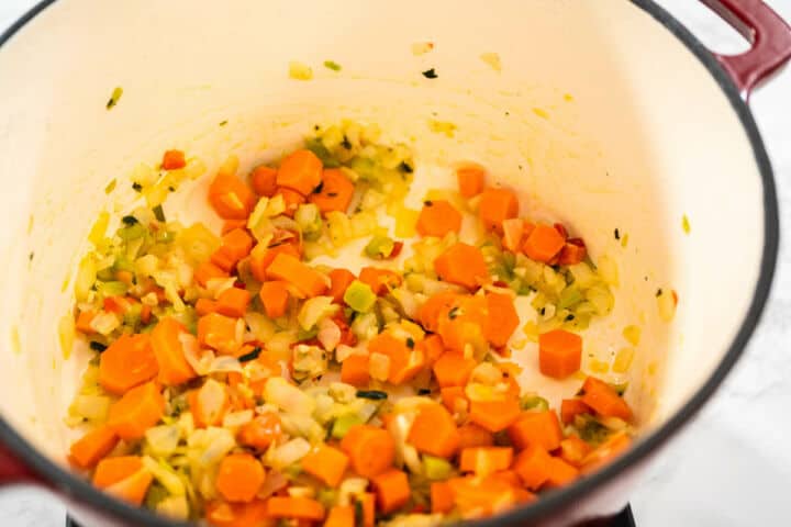 Diced chicken added to sauteed vegetables in a Dutch oven for chicken fideo soup.