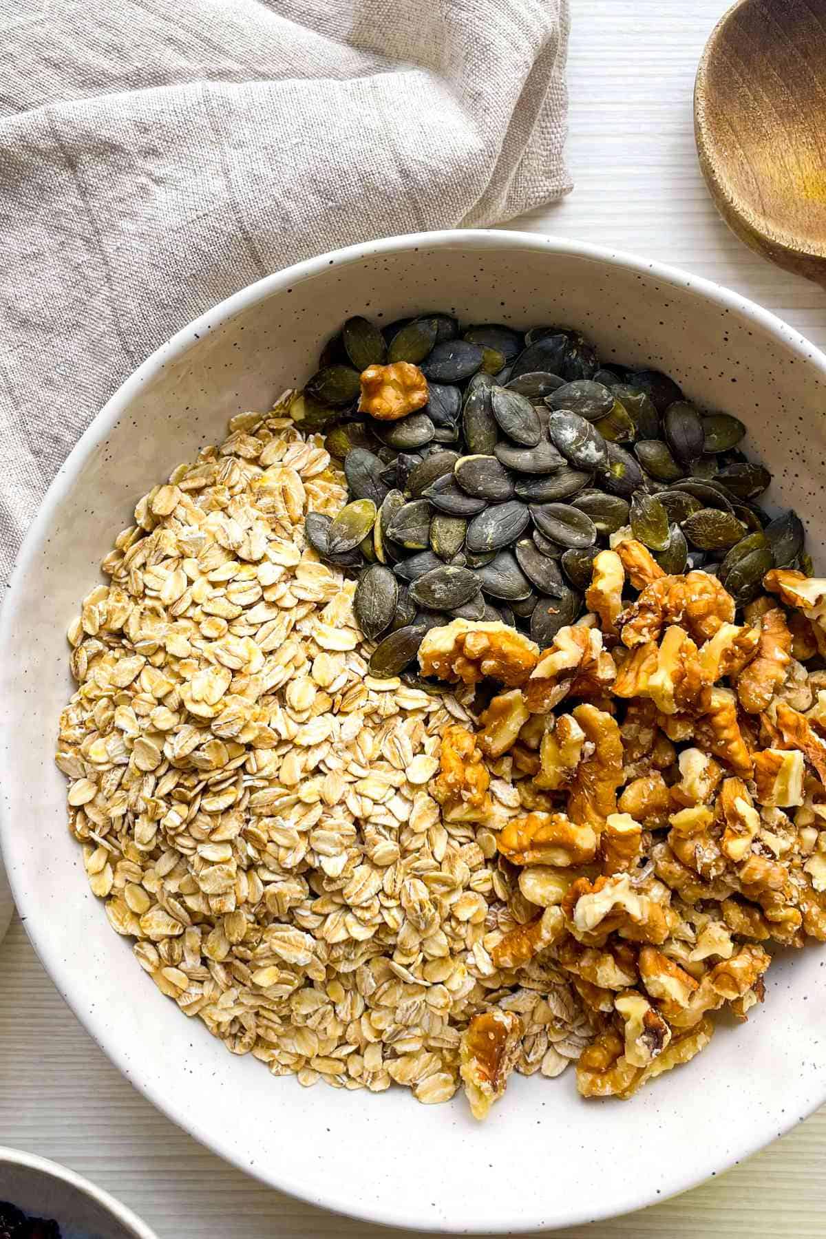 nuts added to bowl of oats and pumpkin seeds.