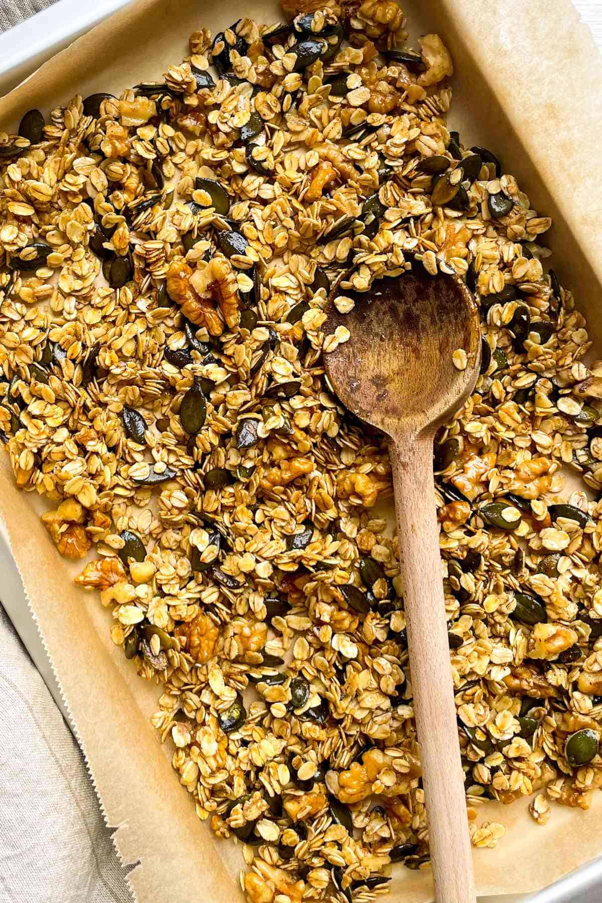 oat, nuts, and seed mixture spread out on a parchment covered baking sheet.