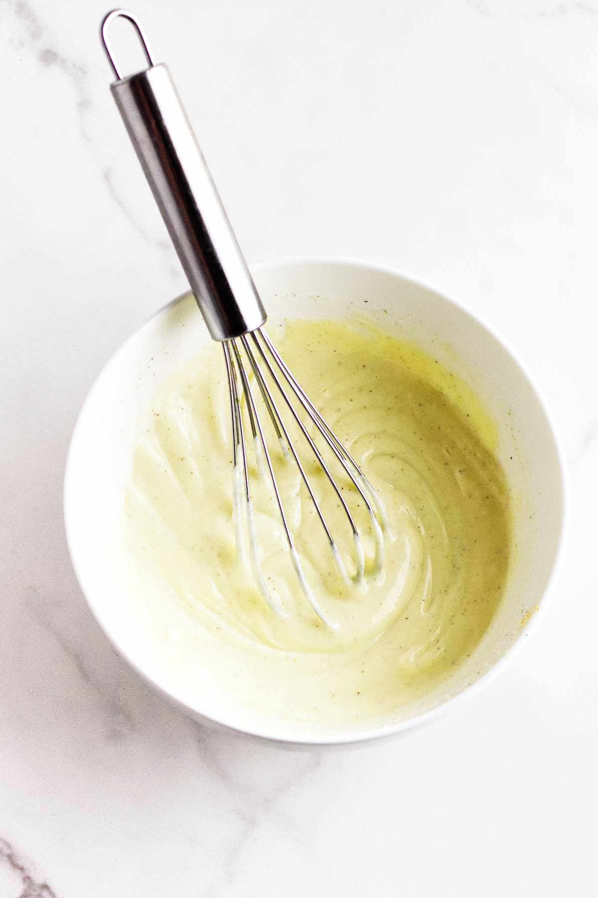 whisk in a bowl of blended white sauce.