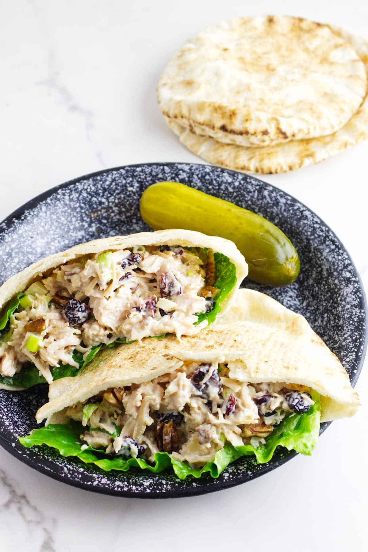 cranberry pecan chicken salad in pita pockets on a plate with a dill pickle - oktoberfest dinner recipes.
