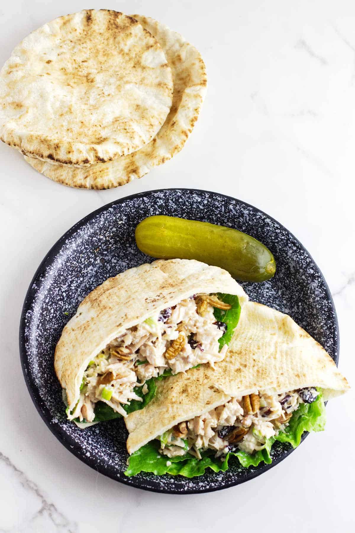 cranberry pecan chicken salad in pita pockets on a plate with a dill pickle.