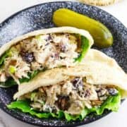 cranberry pecan chicken salad in pita pockets on a plate with a dill pickle.