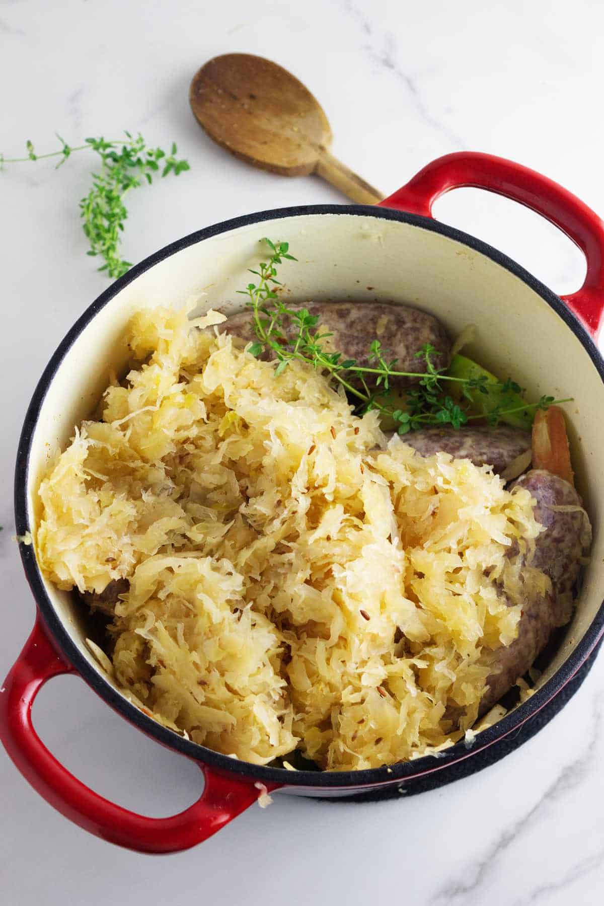 Bavarian sauerkraut on top of brats in a Dutch oven.