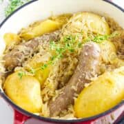 German bratwurst, potatoes, and sauerkraut in a Dutch oven.