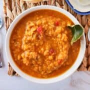 curried Indian red lentil soup with bread and butter nearby.