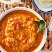 curried Indian red lentil soup with bread and butter nearby.