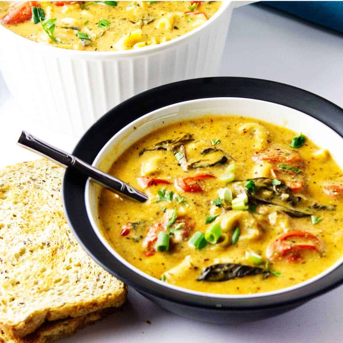 Instant pot tortellini soup in a bowl with toasted bread nearby.