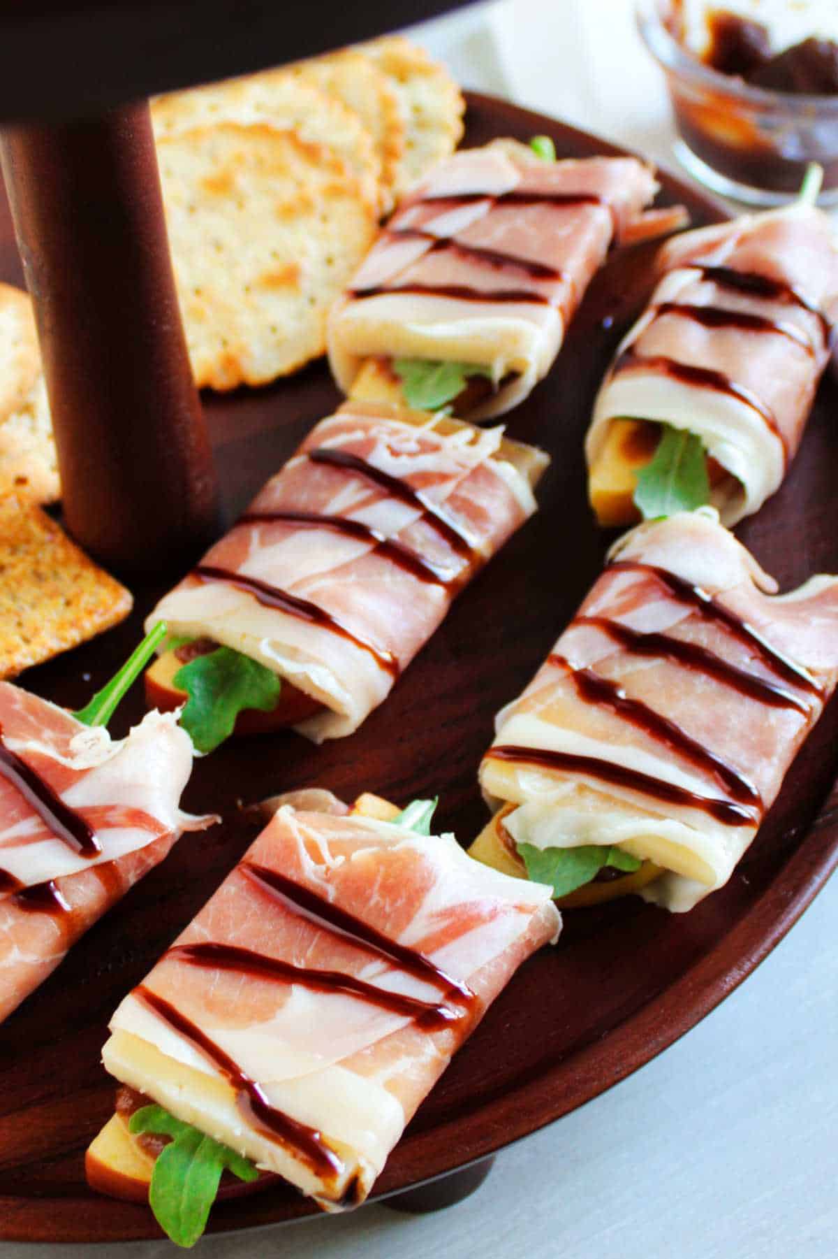 prosciutto wrapped bundles of apple and cheese drizzled with balsamic glaze.