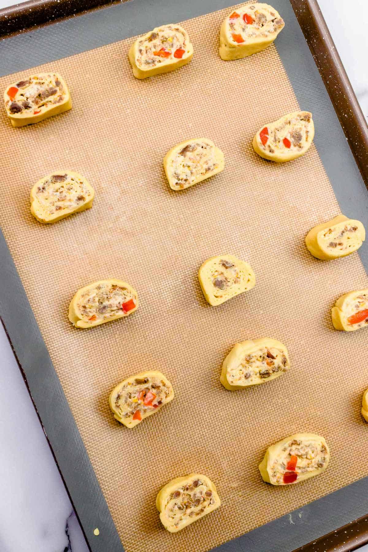 slices of rolled appetizers on a baking sheet.