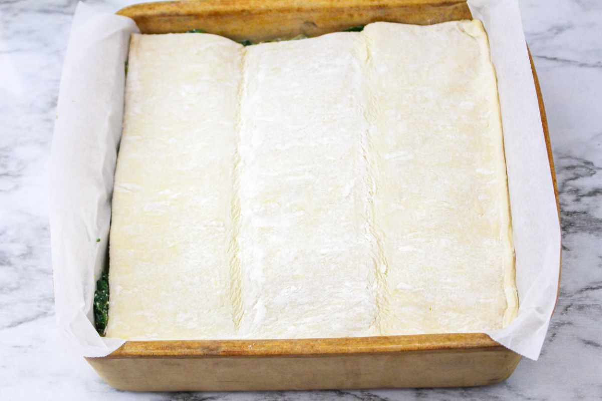 defrosted puff pastry laid on top of spinach and cheese pie filling.