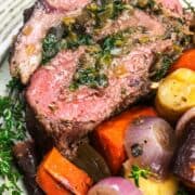 serving of sliced stuffed beef tenderloin on a plate with rainbow carrots.