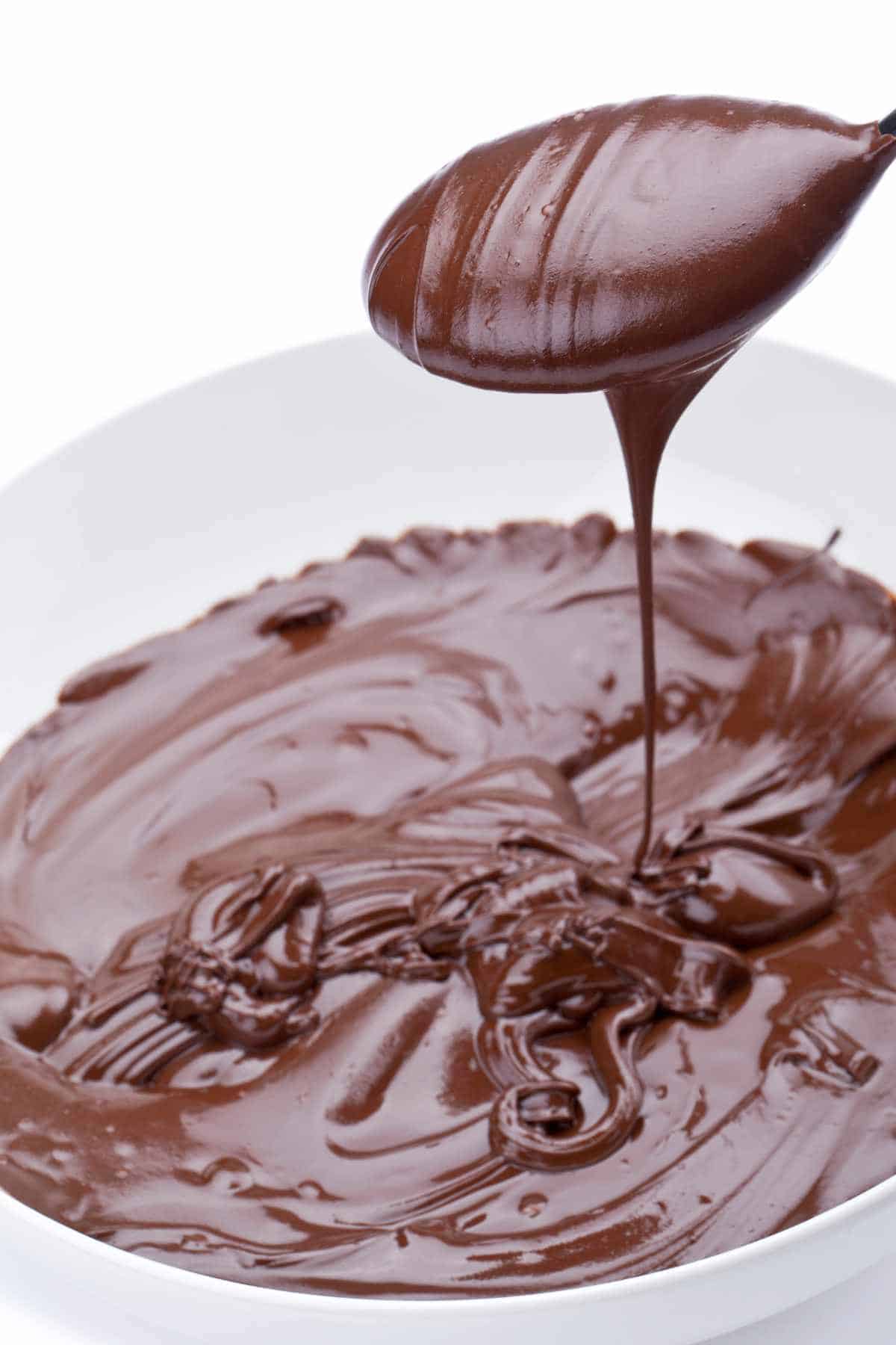 a spoon scoop in melted chocolate ganache.