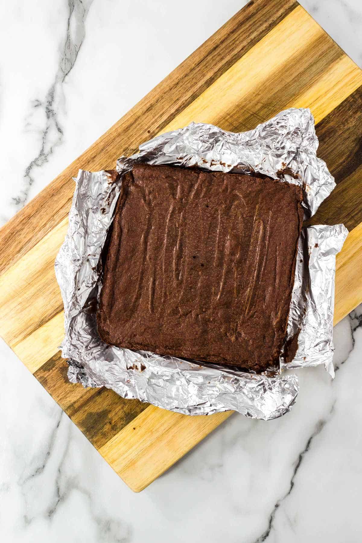 slab of brownies lifted out of the pan with the aluminum foil liner.