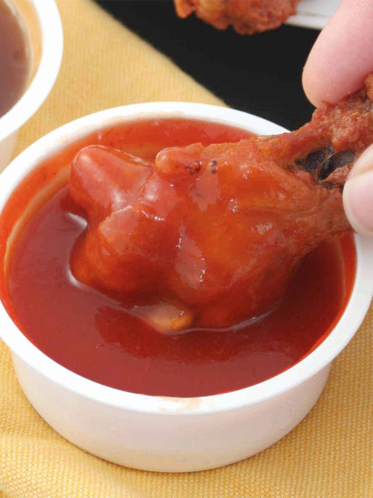 dipping a chicken wing into a spicy buffalo sauce.