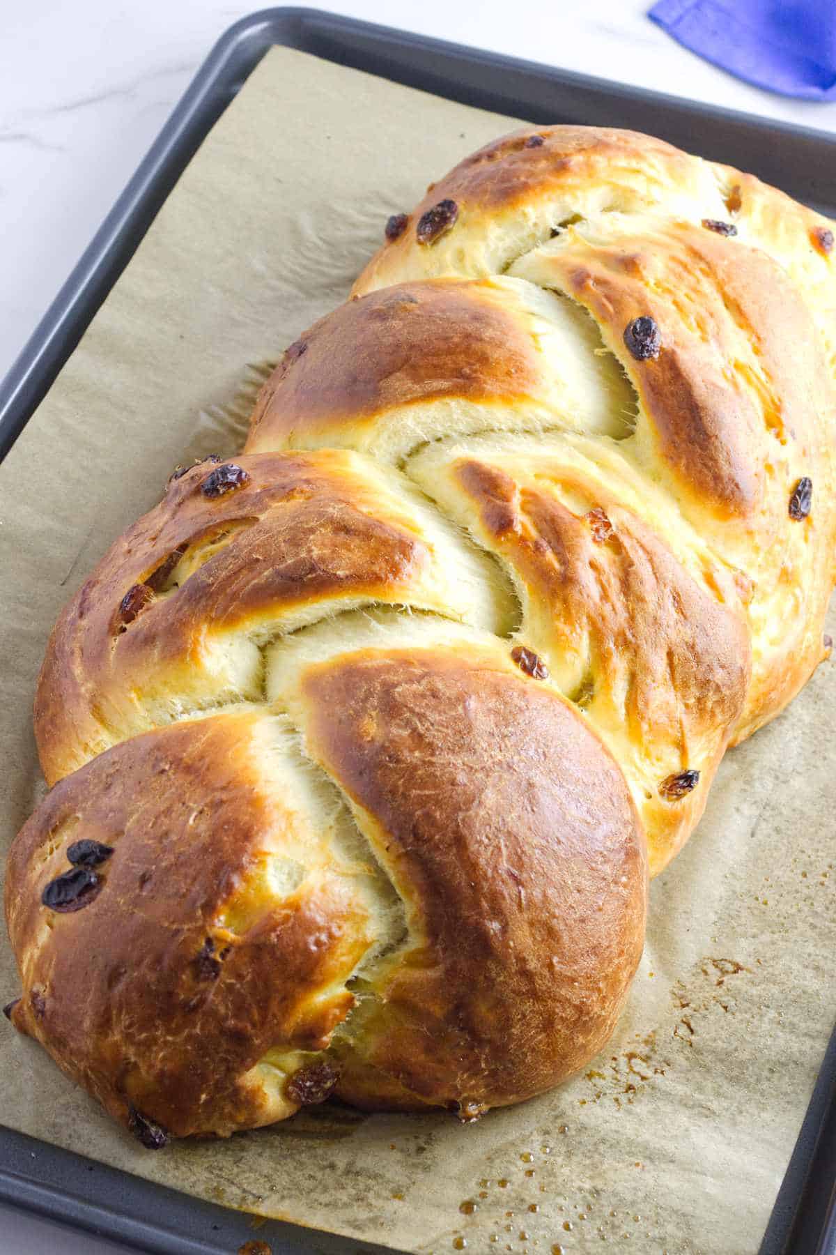 baked challah with raisins on a baking sheet.