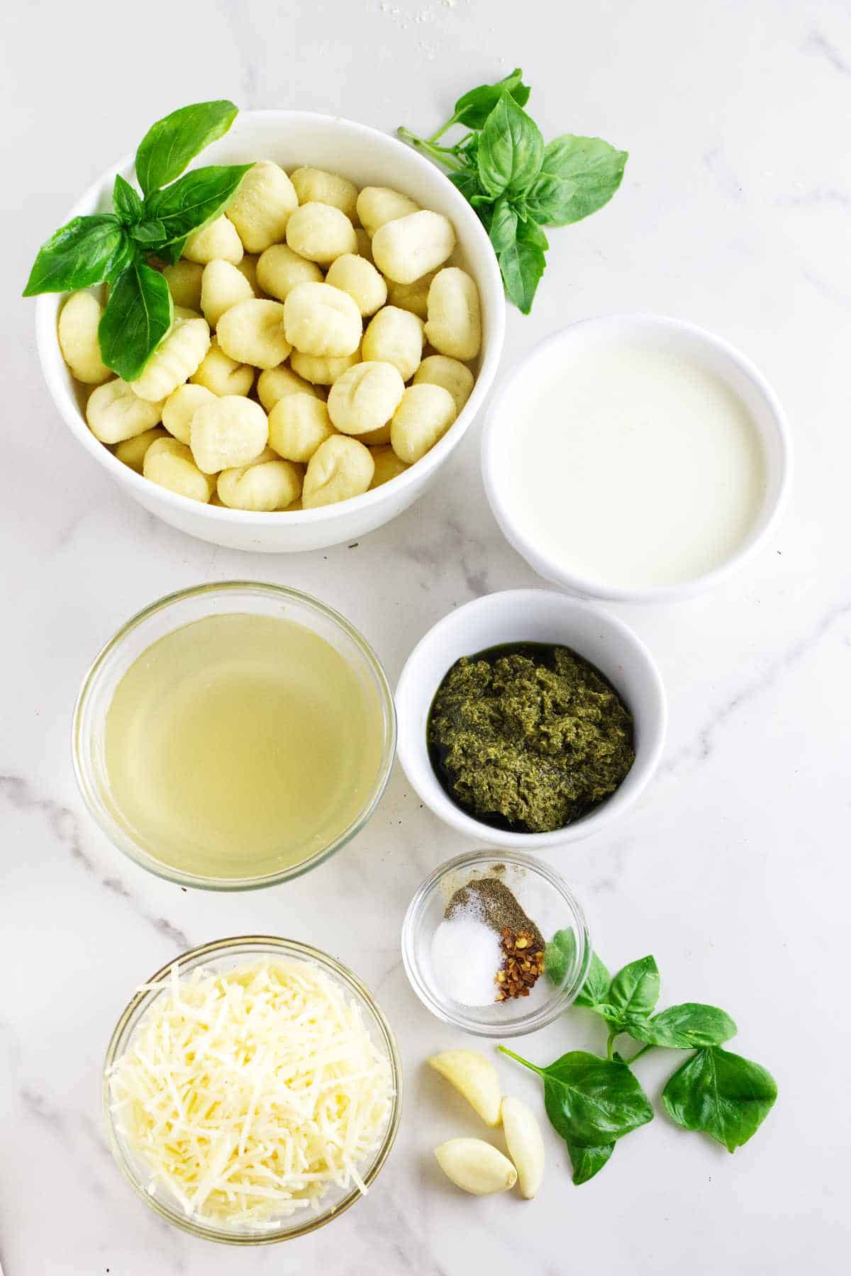 potato gnoochi, broth, Parmesan cheese, and pesto on a white background.