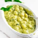 oval baking dish serving creamy pesto gnocchi.