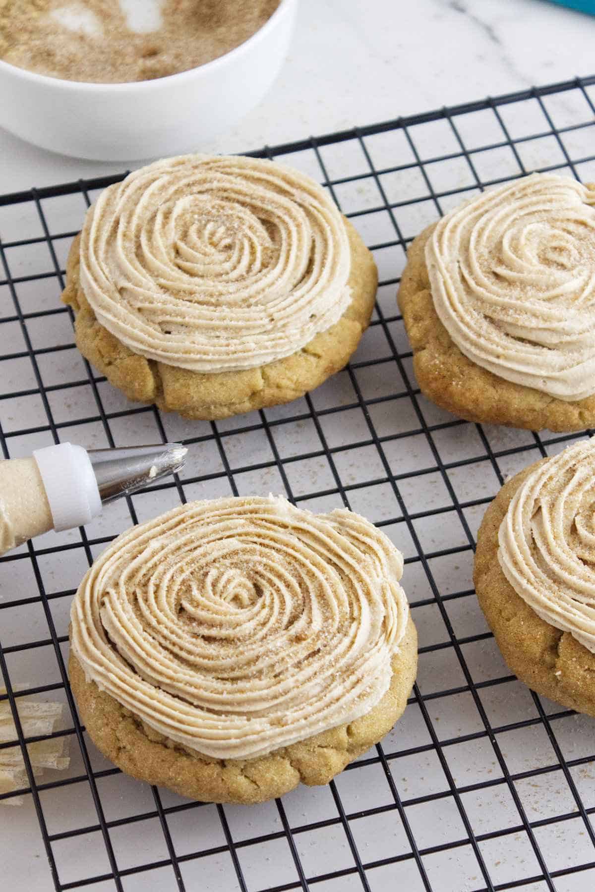 frosted cinnamon churro Crumbl cookies on a cookie rack.