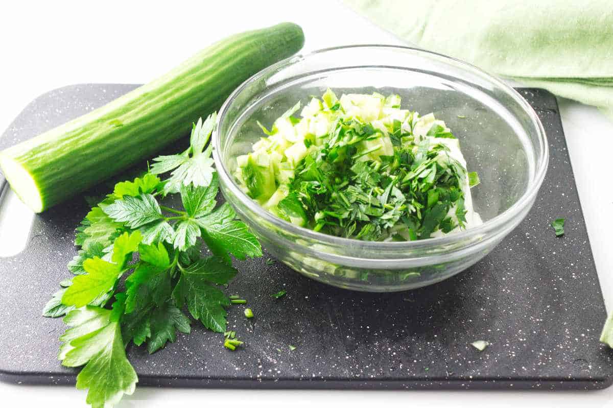 chopped cucumber and parsley in a mixing bowl.