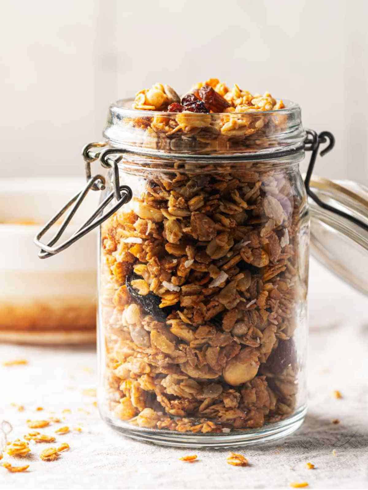Delicious homemade granola in glass jar on white background.