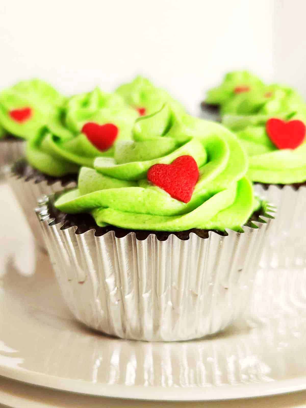 Red candy hearts on green frosting iced cupcakes.