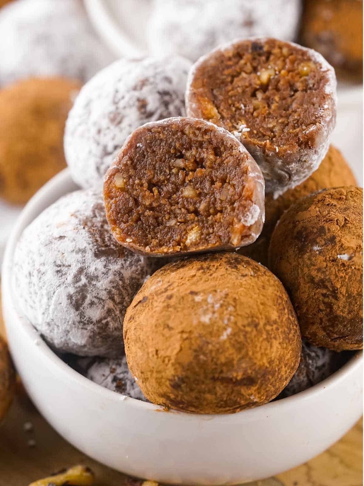 close up of a bowl of rum balls, with one cut to show the center.