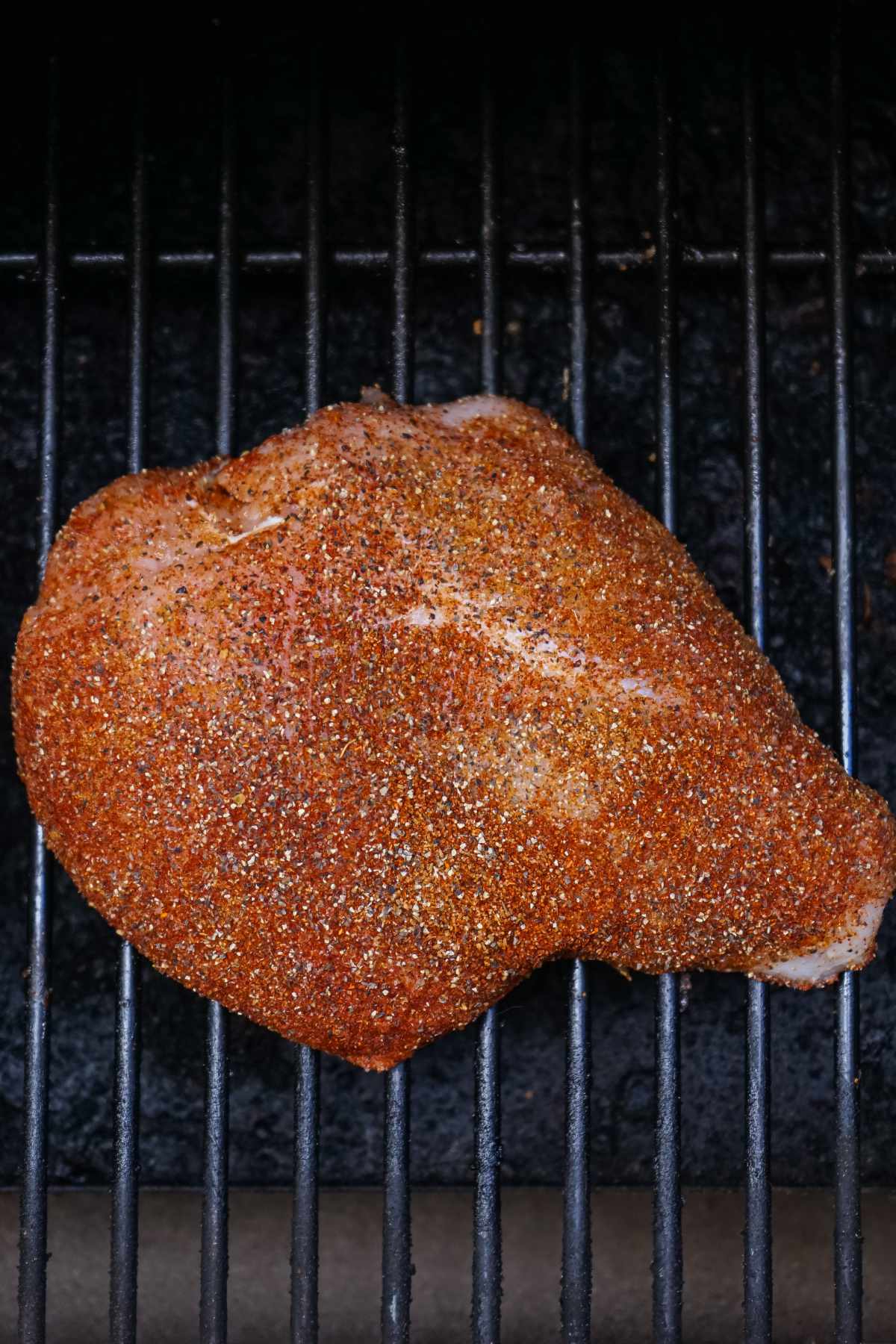 seasoned boneless turkey breast on a smoker grill.