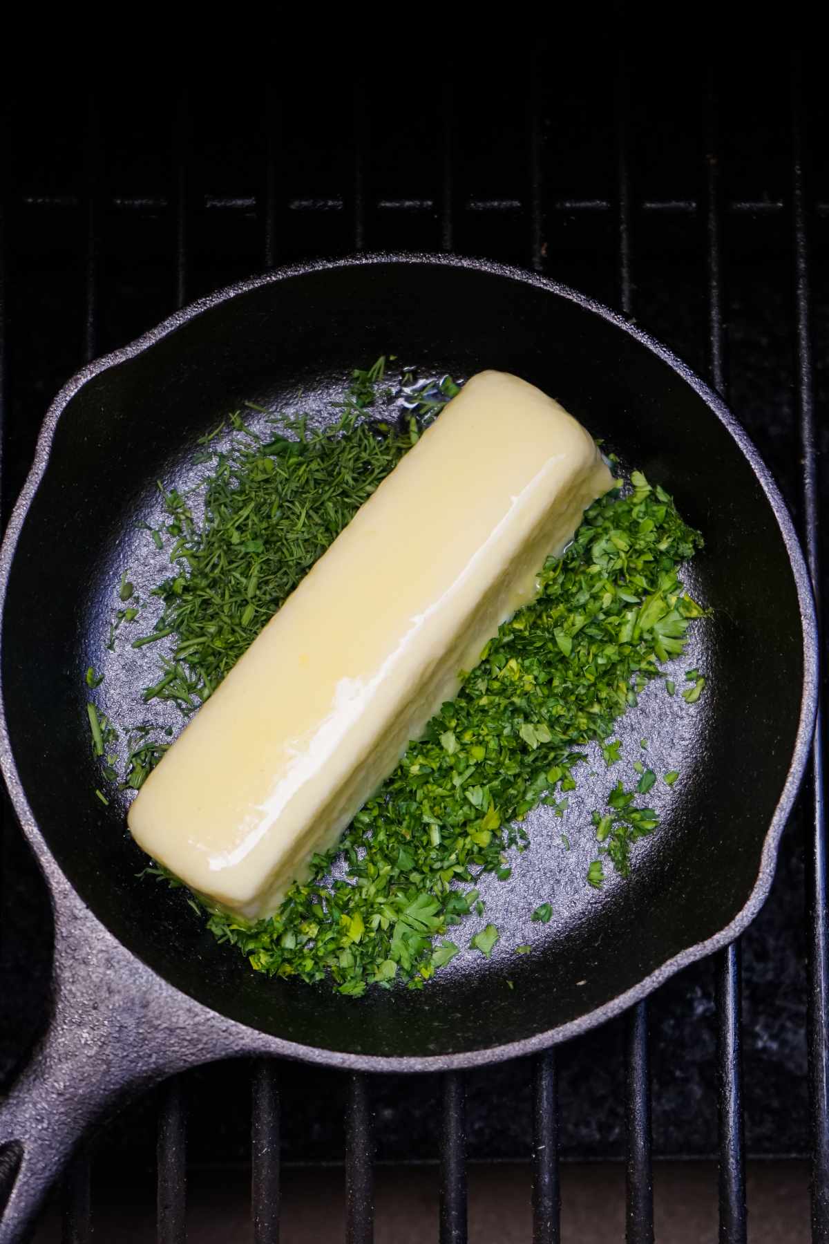 butter and parsley in a small cast iron skillet on a grill.