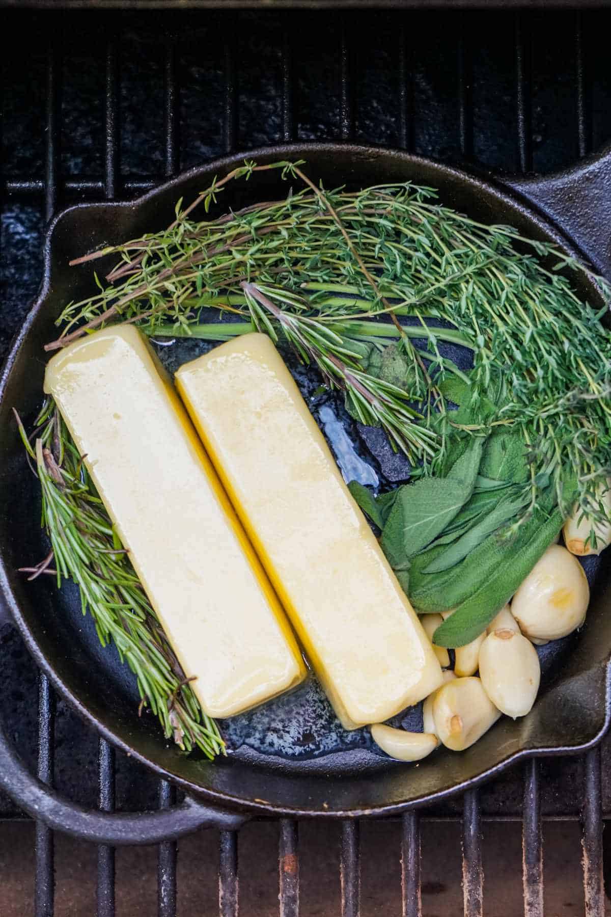 butter and herbs in a cast iron skillet on a grill.