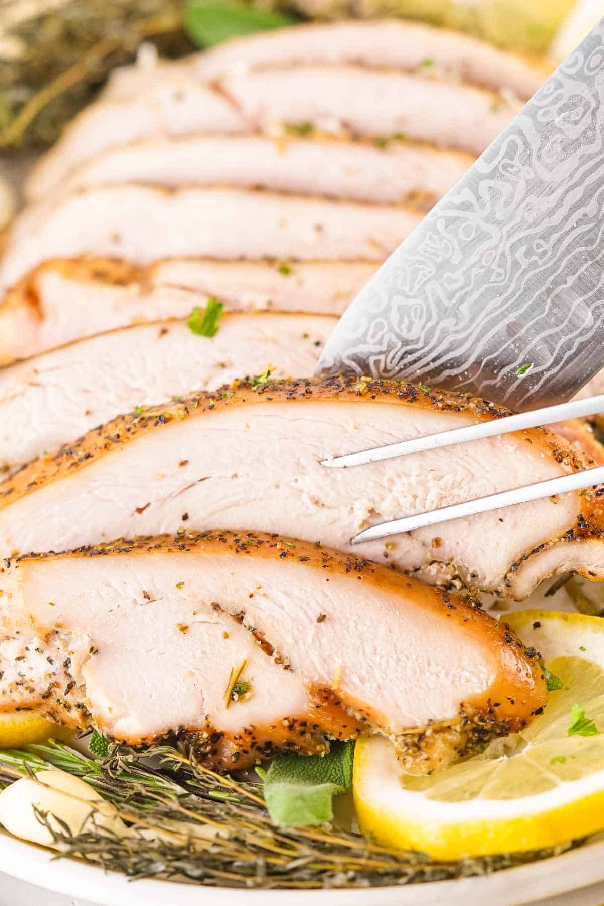 carving a boneless turkey breast with sharp knife.