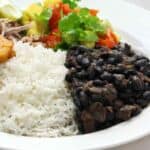 serving bowl with cuban black beans, tostones, cilantro and red onion.