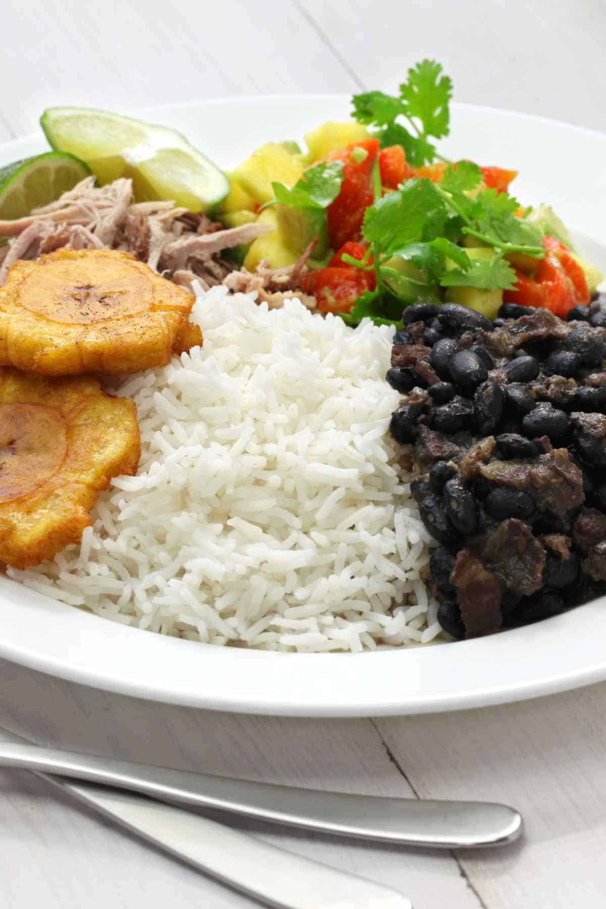 serving bowl with cuban black beans, tostones, cilantro and red onion.