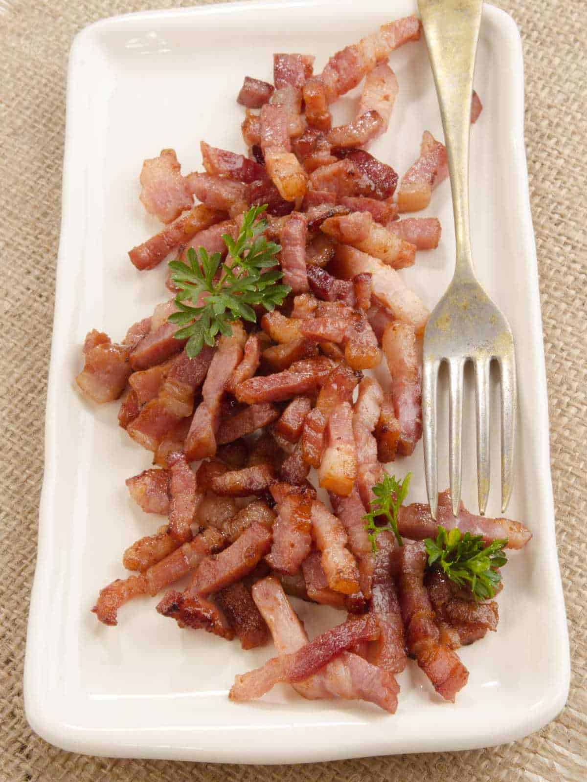 grilled bacon bits on a plate with parsley and fork.