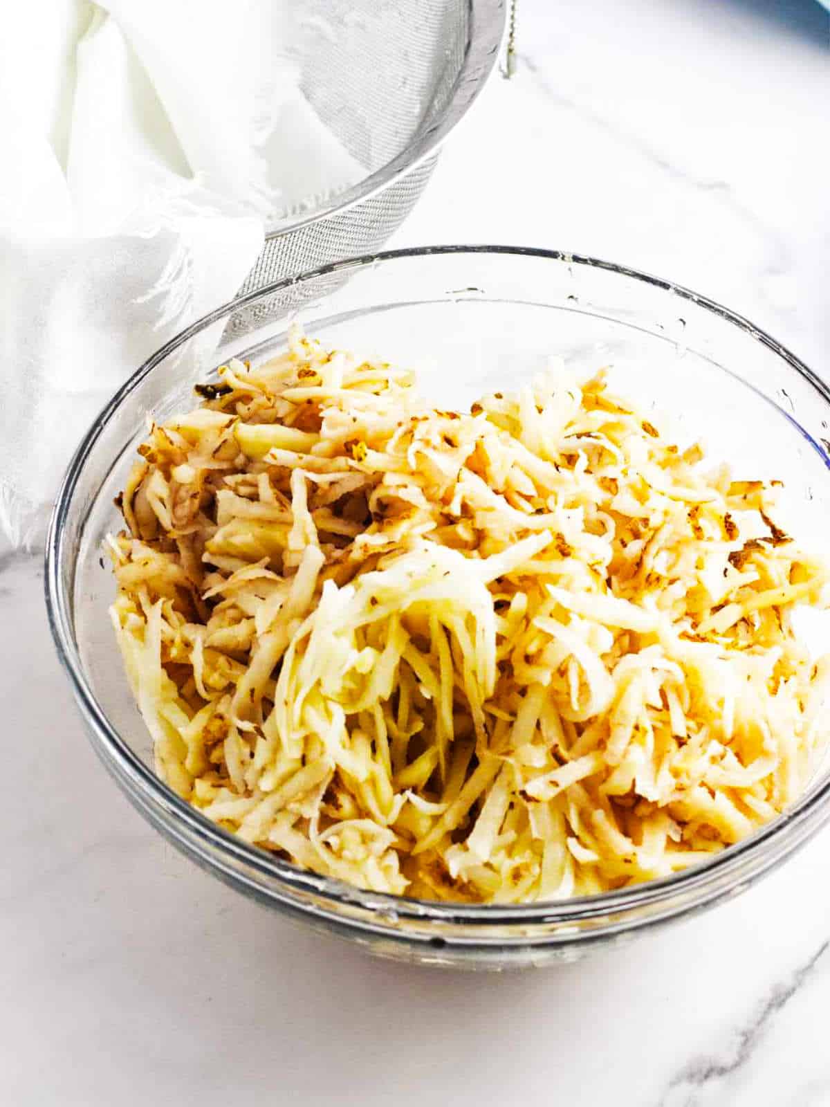 Shredded potatoes in a mixing bowl.