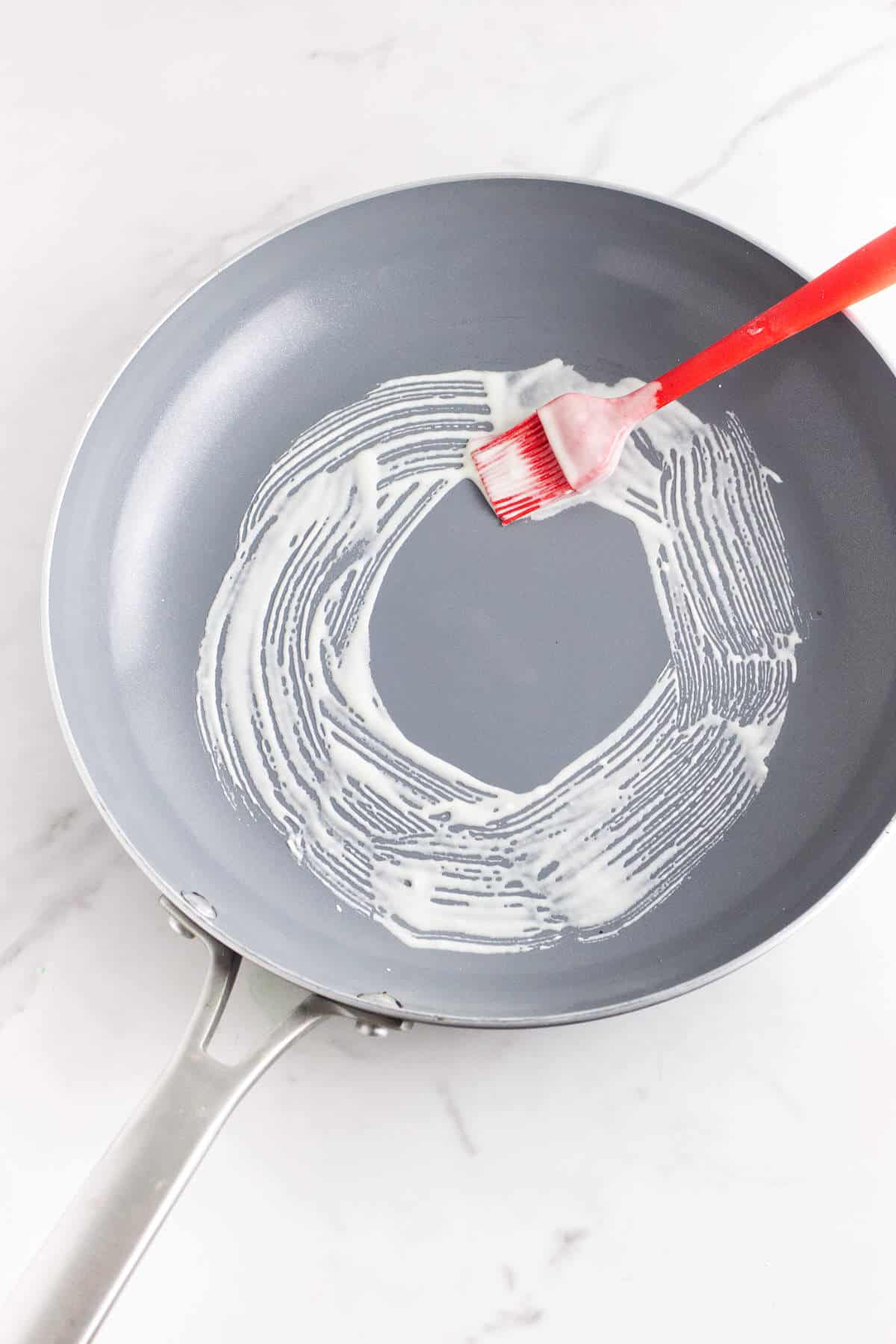 brushing batter in a circle in a non stick skillet.