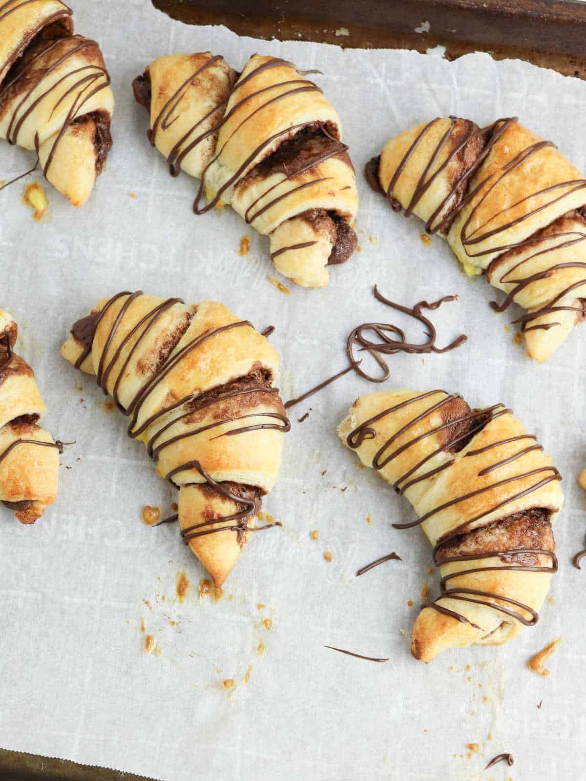 baked crescent rolls with chocolate drizzled on them.