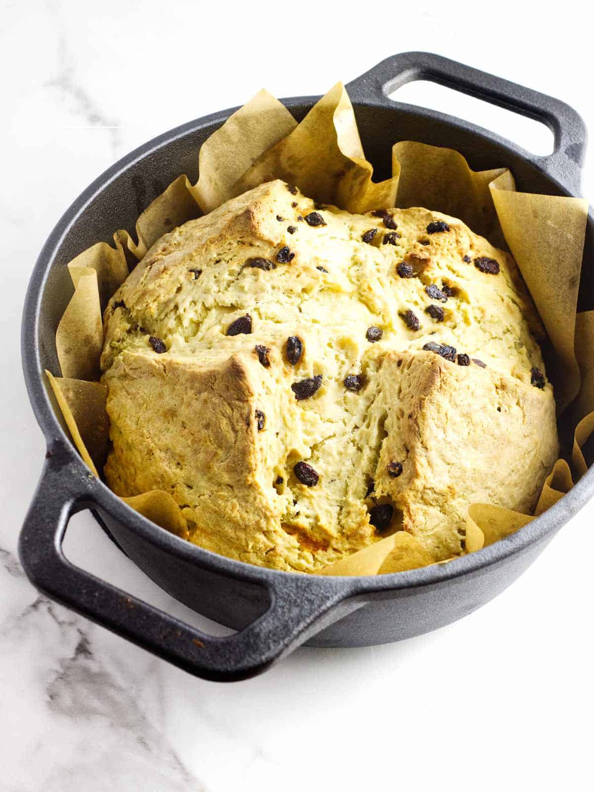 Baked soda bread with raisins in a Dutch oven.