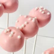 strawberry cake pops with white sprinkles on top.