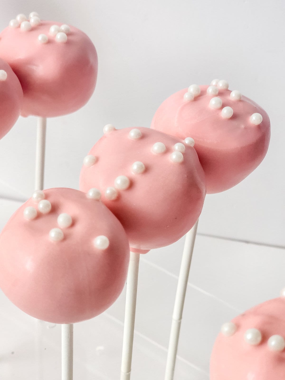 strawberry cake pops with white sprinkles on top.