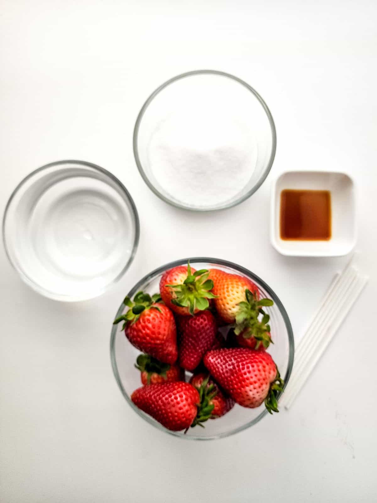 bowls of sugar, water, vanilla, and fresh strawberries.
