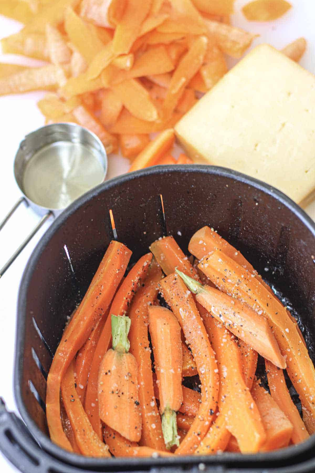 seasoned carrots in an air fryer basket.