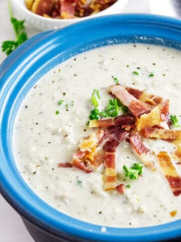 Mock potato soup (celery root soup) with bacon and parsley garnish in a soup bowl.