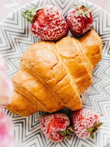 croissant on a plate with sugared strawberries.