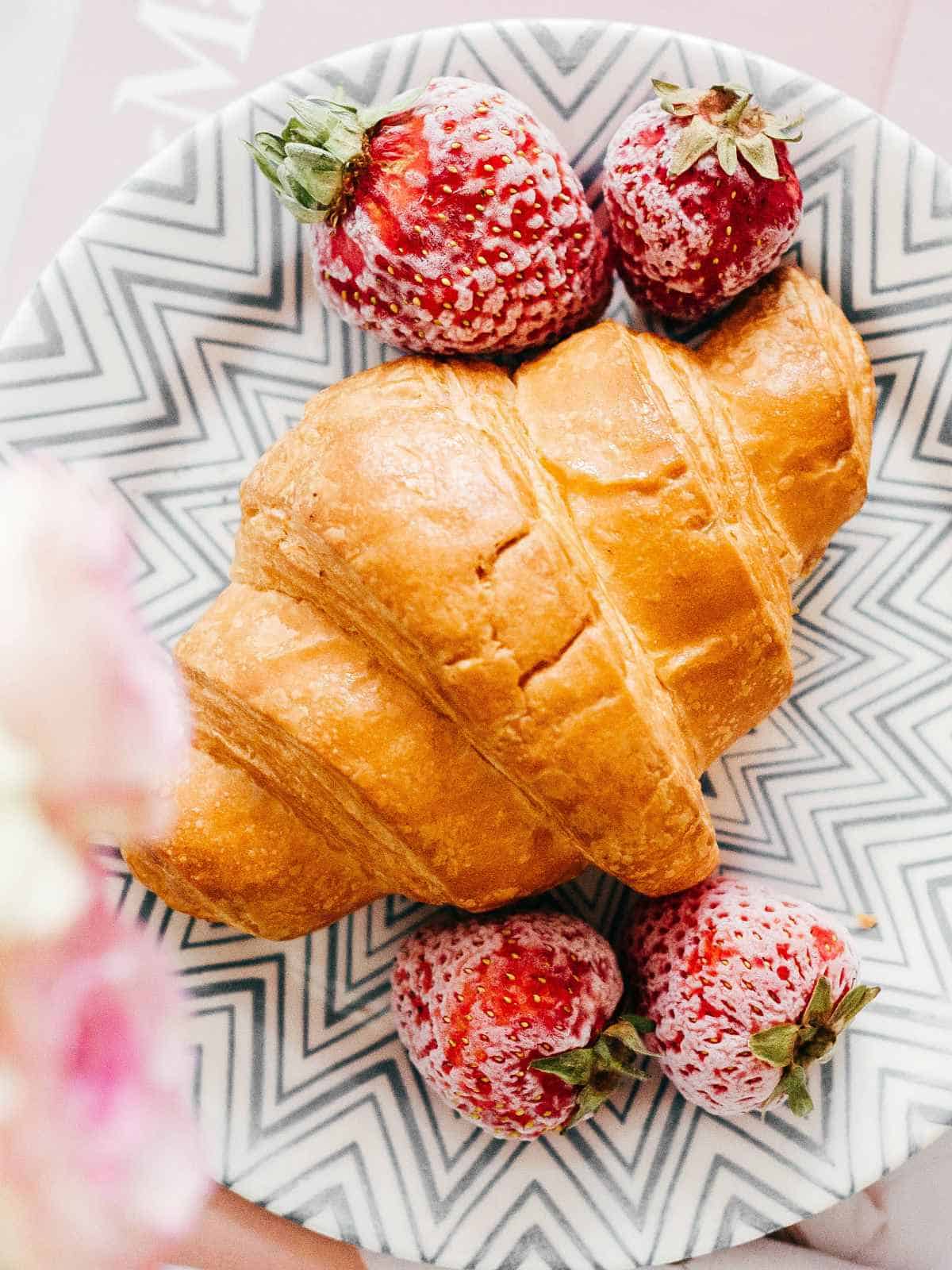 croissant on a plate with sugared strawberries.