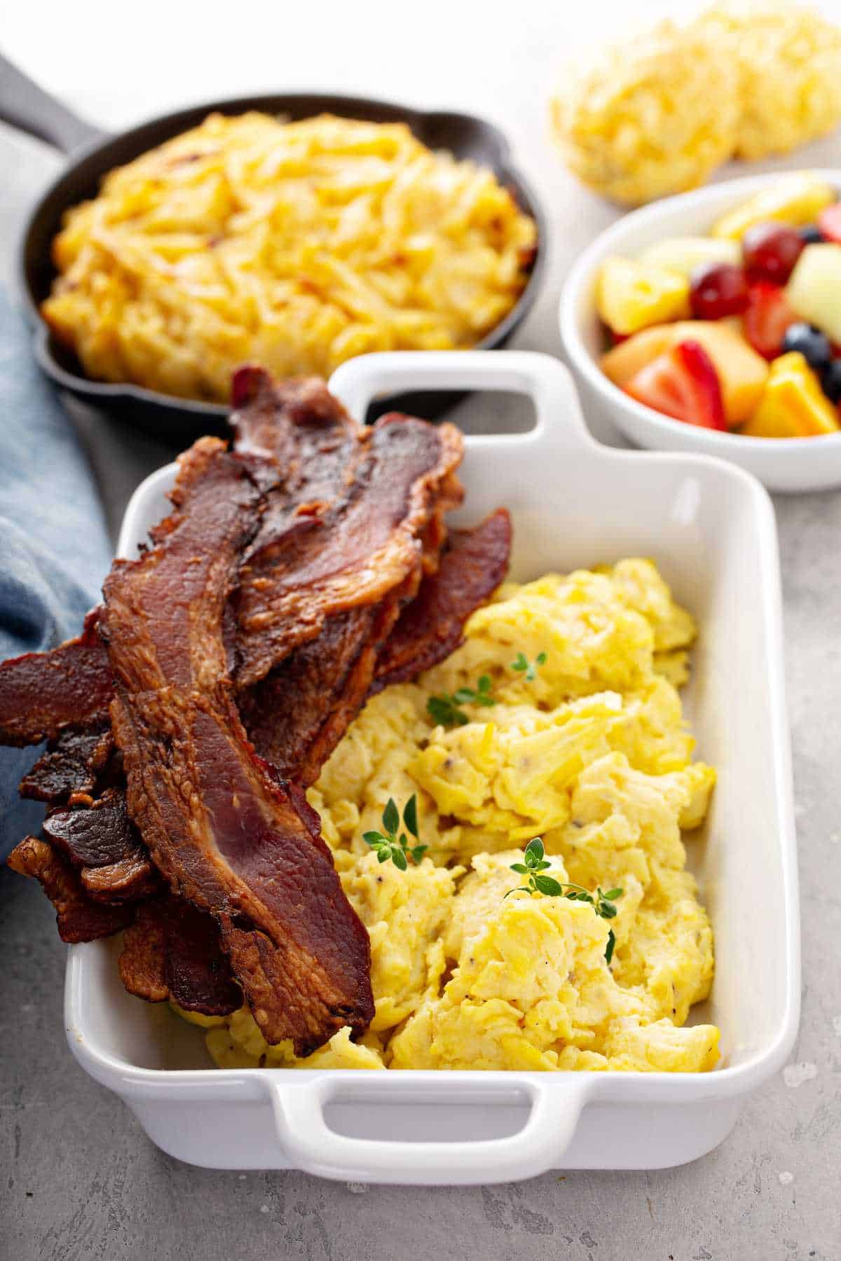 Full brunch with scrambled eggs, bacon and hash brown potatoes.