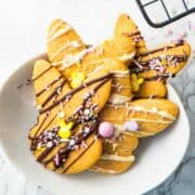 sprinkle decorated, white and dark chocolate drizzled bunny shaped Easter sugar cookies in a serving bowl.
