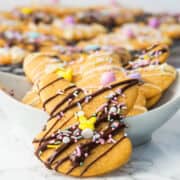 sprinkle decorated, white and dark chocolate drizzled bunny shaped Easter sugar cookies in a serving bowl.