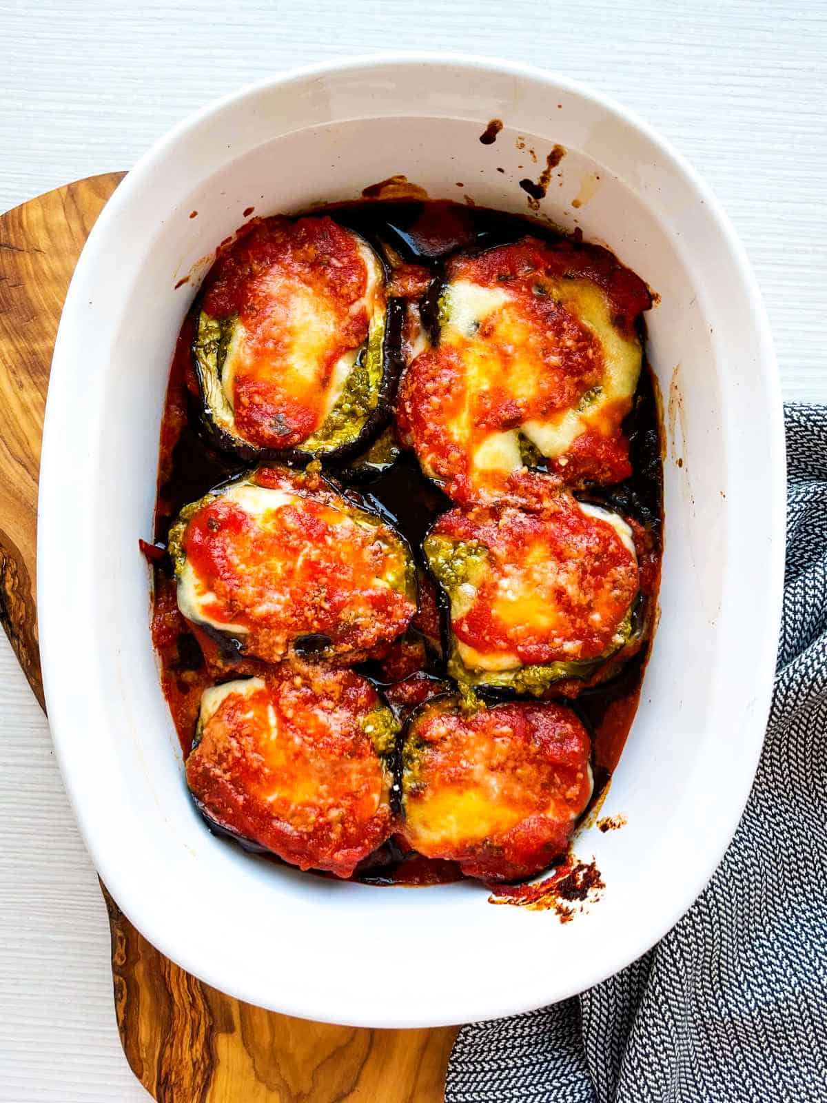 mozzarella and cheese on top layer of casserole of eggplant Parmesan stacks.