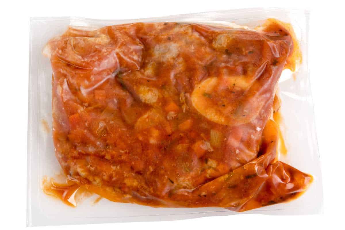 Vacuum packed meal of prepared ossobucco with veal in a wine and fruit sauce in an air-tight plastic bag for freezing or to extend shelf life.